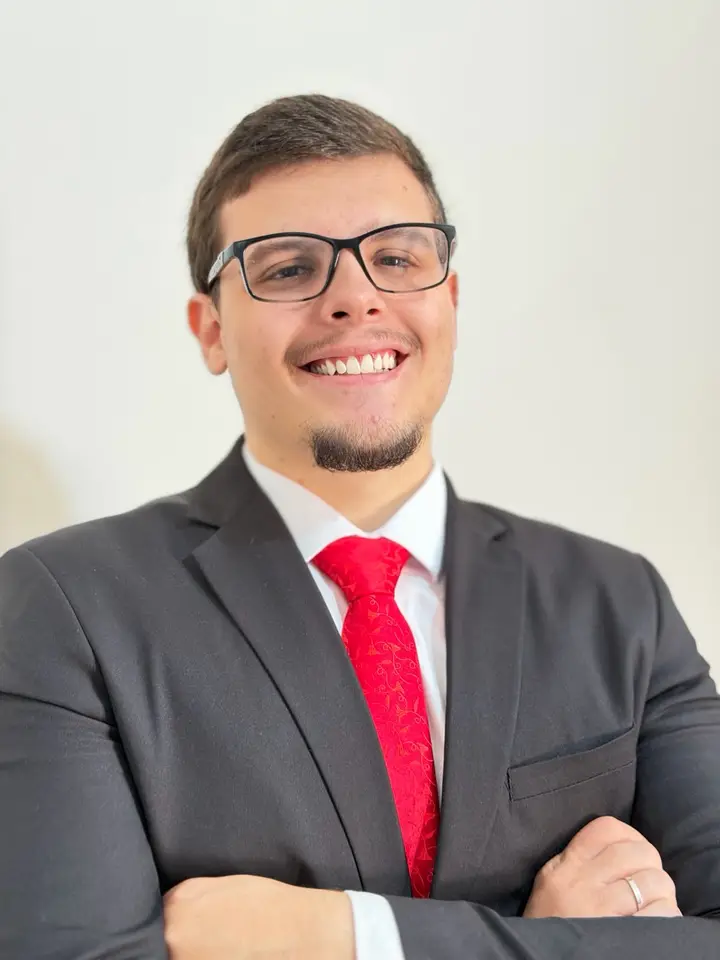 Pedro Crepaldi, advogado, sorrindo, de terno escuro e gravata vermelha, com os braços cruzados